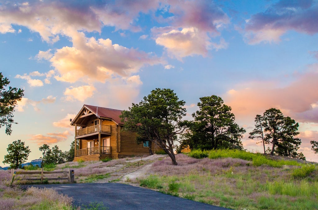 Rustic luxury ranch nestled near Zion National Park, with wooden cabins, mountain silhouettes, and warm sunset hues illuminating a serene landscape