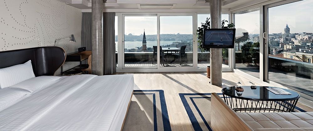 Luxurious penthouse suite at Witt Istanbul Hotel with modern design, floor-to-ceiling windows, sleek furnishings, and panoramic city skyline view.