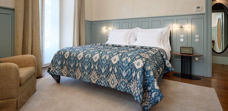 Elegant hotel room with ornate gold-framed mirror, plush double bed, antique-style furniture, and traditional Portuguese decor in muted tones