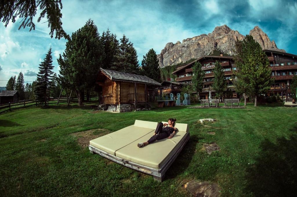 Historic Italian alpine hotel with stone and wood facade nestled in snow-covered Dolomite mountains, featuring traditional architecture