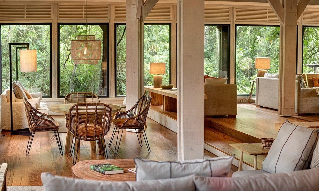 Two-story luxury jungle villa with private deck, floor-to-ceiling windows, and wooden accents nestled among lush rainforest canopy