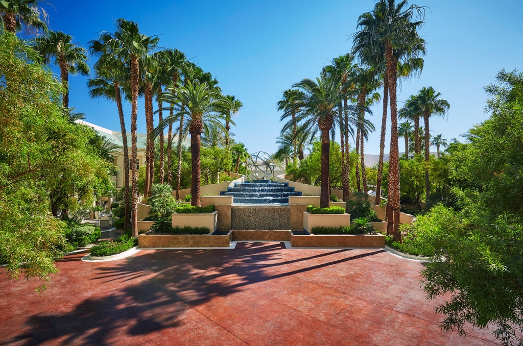 Elegant high-rise Four Seasons hotel tower with glass facade reflecting golden sunlight, rising above palm trees and manicured gardens in Las Vegas