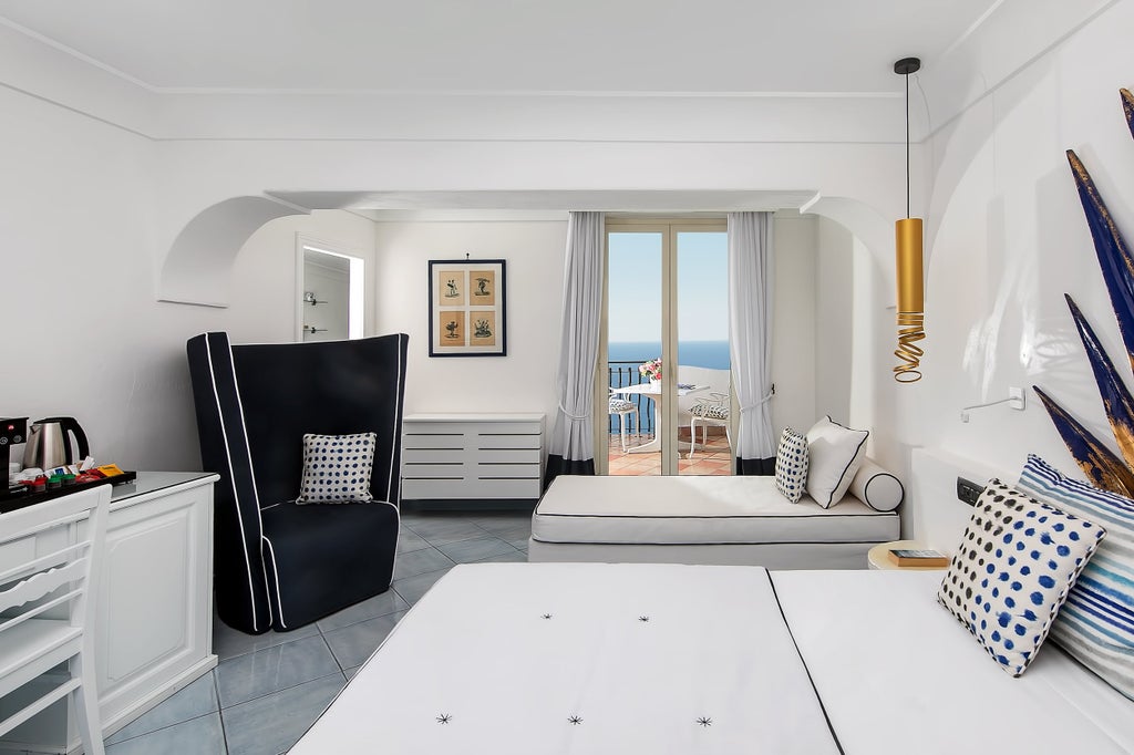 Modern elegant hotel room with panoramic Mediterranean Sea views, featuring balcony, white decor, and plush king bed with premium linens