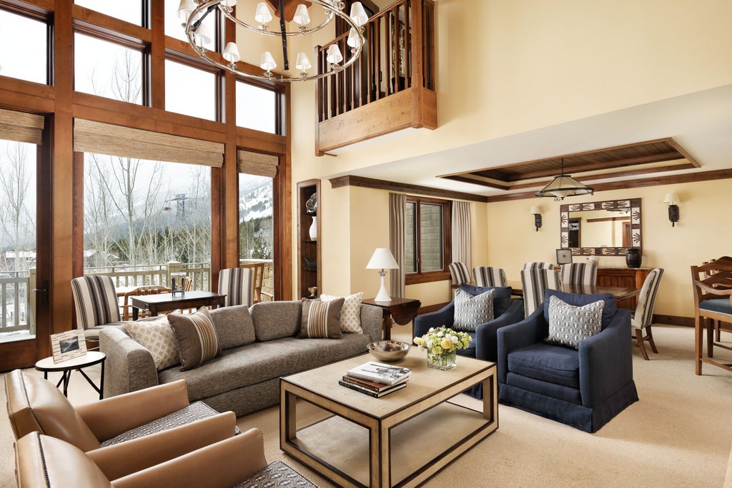 Upscale mountain lodge resort with snow-dusted peaks backdrop, featuring stone and timber facade, grand entrance and luxury balconies