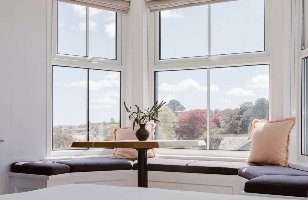 Luxurious king-size bed with crisp white linens, plush throw pillows, and soft neutral decor in modern coastal-style bedroom at seaside hotel suite