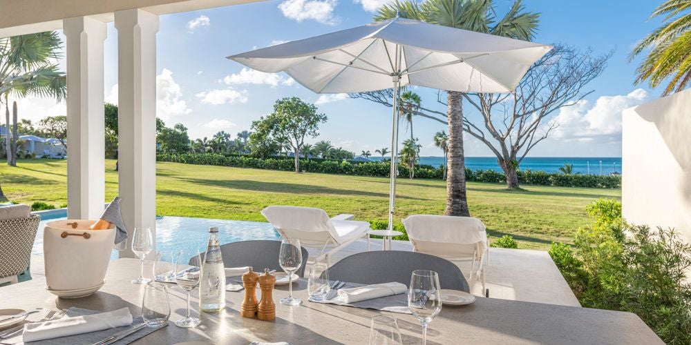 Spacious Jumby Bay Island Family Suite with elegant four-poster bed, Caribbean Sea view, and modern luxurious design in soft neutral tones