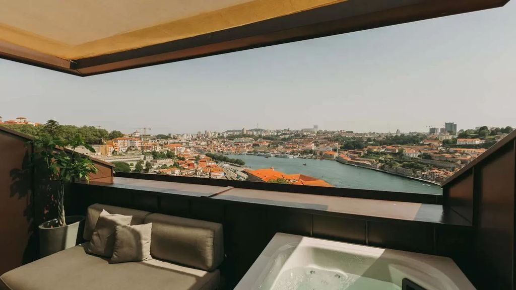 Modern luxury hotel exterior with glass balconies overlooking Porto cityscape, featuring sleek architecture and hillside location at sunset