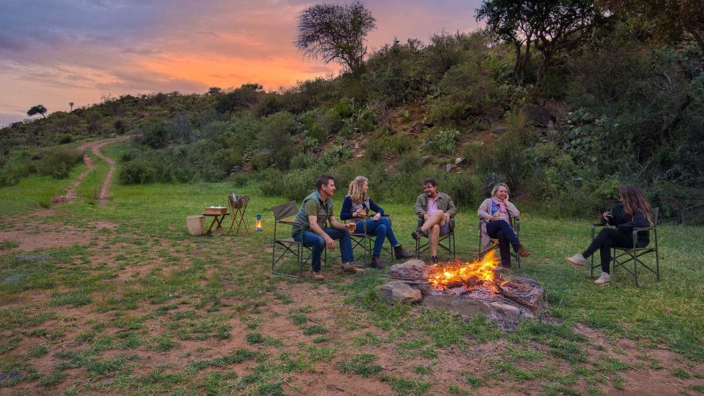 Luxurious safari tents overlooking expansive Kenyan wilderness with dramatic rocky landscape and distant mountain silhouettes at scenic wildlife camp