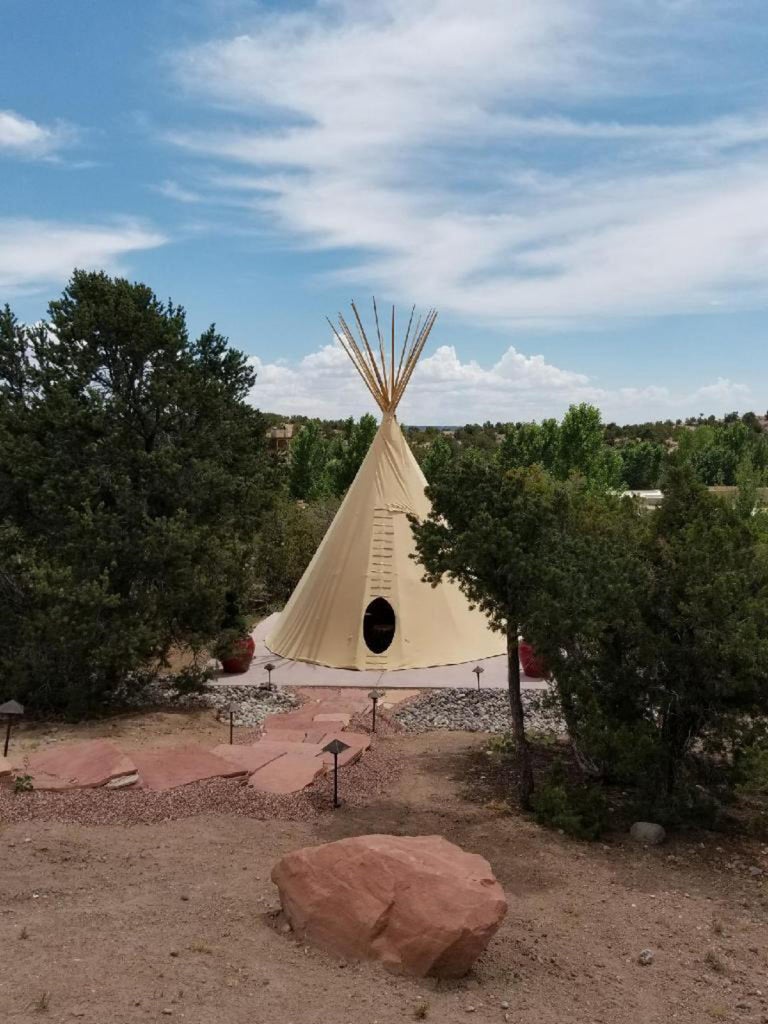 Elegant adobe-style luxury resort with terracotta walls nestled against Sangre de Cristo mountains, surrounded by desert flora and walkways