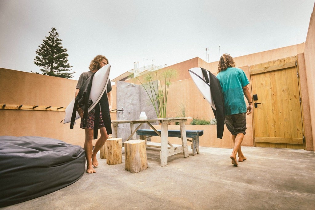 Minimalist bunk bed in coastal-inspired surf hostel room, featuring wooden accents, clean lines, and warm neutral tones overlooking Portuguese shoreline