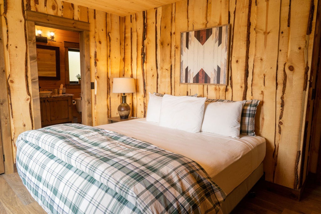 Rustic lodge bedroom with wooden furnishings, mountain-view window, plush king bed, and warm neutral tones at Scenset Mountain Ranch accommodation.