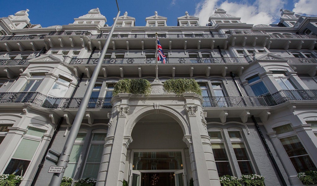 Elegant boutique hotel facade with Victorian architecture, ornate windows, and soft lighting, showcasing luxurious design in central London location