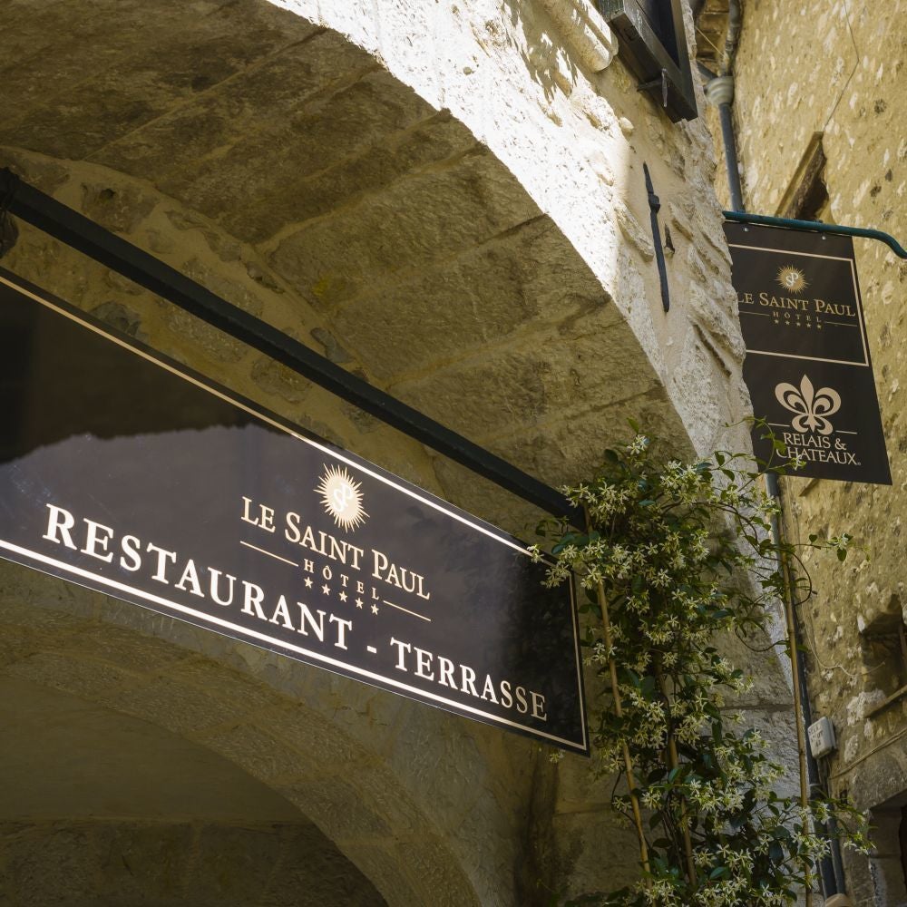 Elegant stone facade of boutique Hotel in charming French town, traditional architectural details, warm sunlight, luxurious historic exterior