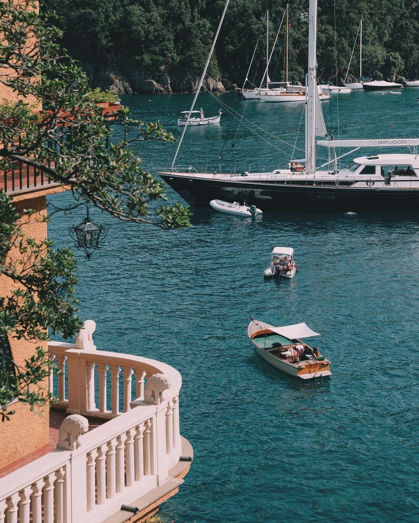 Elegant five-star coastal hotel with Mediterranean architecture, infinity pool overlooking Amalfi cliffs and azure waters at sunset