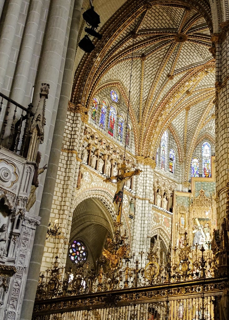 Panoramic view of Toledo's golden historic skyline, medieval stone architecture, sunlit cathedral spires, and distant Spanish landscape under soft afternoon light