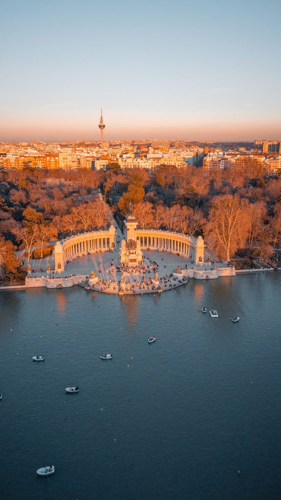 Sunset illuminates Madrid's iconic Metropolis Building with ornate Baroque architecture, golden domes gleaming against deep blue sky