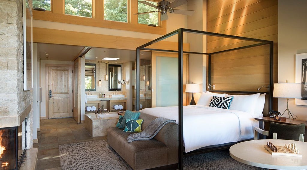 Luxurious Pacific House Suite overlooking rugged coastline, featuring elegant natural wood furnishings and expansive floor-to-ceiling windows with Pacific Ocean view