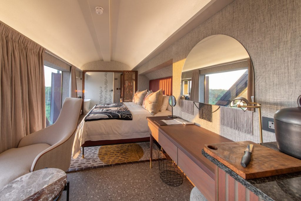 Art deco-style luxury train hotel suspended over Sabie River, featuring glass-walled suites with panoramic views of Kruger National Park