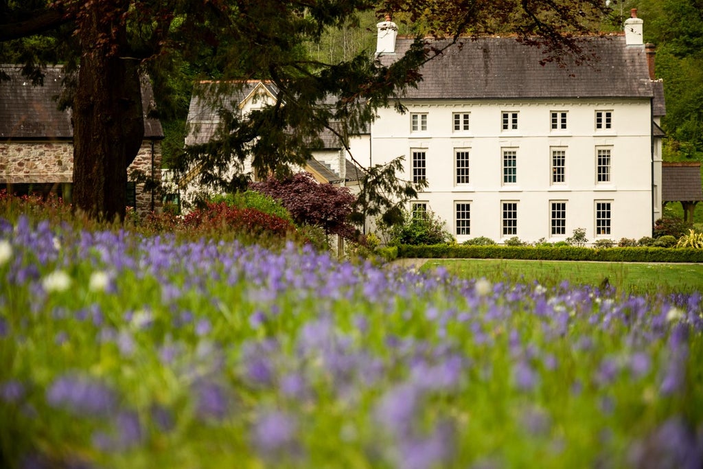 Elegant stone country house hotel nestled in lush green countryside, featuring traditional Welsh architecture with manicured gardens and soft natural lighting