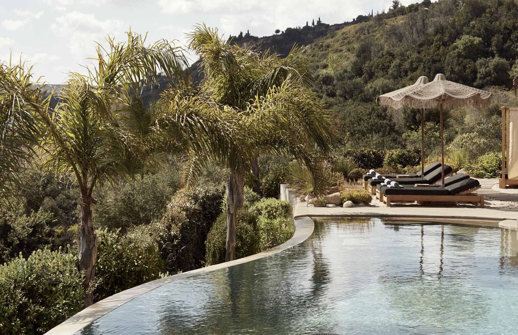 Luxurious white-washed Greek villa with infinity pool overlooking azure Kefalonian coastline, surrounded by lush Mediterranean greenery at sunset