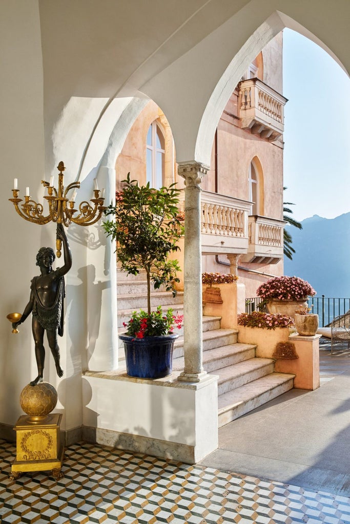 Pink-hued luxury Italian palazzo hotel perched on Amalfi Coast cliffs, featuring elegant terraces and panoramic Mediterranean views