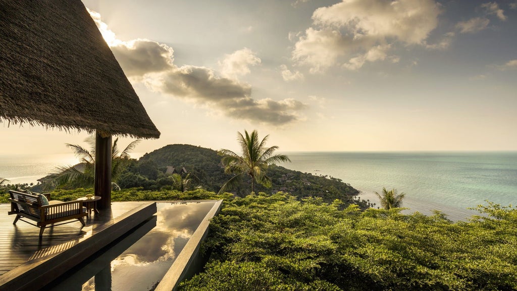 Luxurious infinity pool overlooking turquoise ocean at Four Seasons Samui, with tropical palm trees and private cabanas at sunset