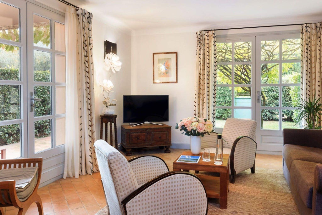 Elegant stone-walled French hotel room with antique furnishings, cream linens, and a luxurious four-poster bed in a historic Provençal abbey setting