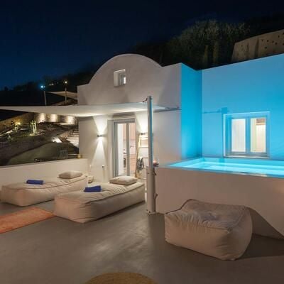 Elegant white-washed garden suite with private terrace overlooking azure Aegean Sea, featuring minimalist decor and traditional Cycladic architectural design