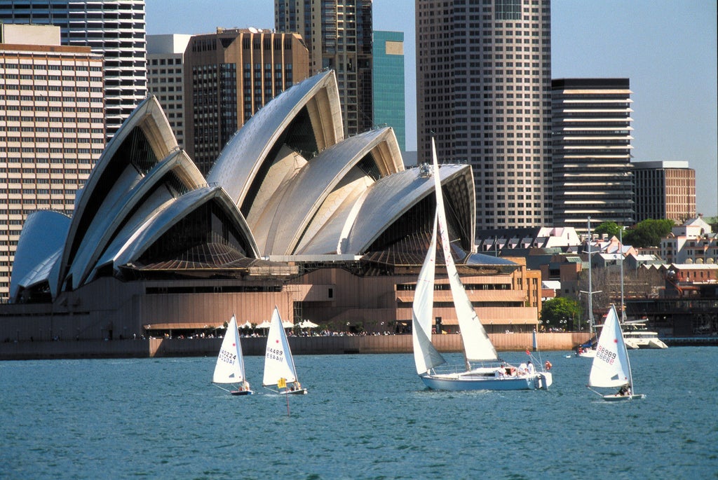 Modern glass skyscraper of Four Seasons Hotel Sydney rising above Circular Quay, featuring sleek architecture and harbor views at golden hour