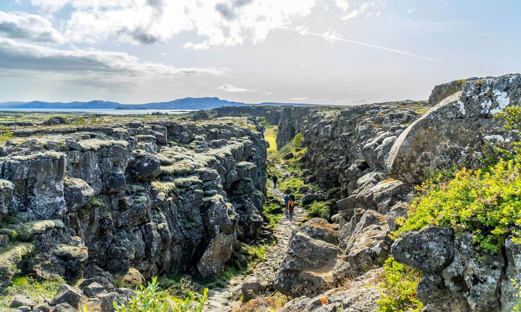 Luxurious Icelandic hotel nestled against dramatic volcanic landscape, featuring rustic wood exterior and panoramic views of geothermal terrain near famous geysers