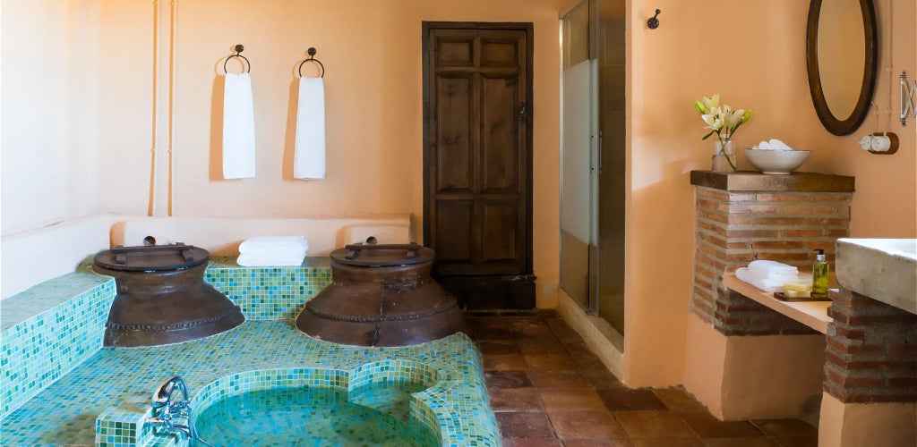 Elegant Spanish country hotel room with whitewashed walls, rustic wooden furniture, and traditional tile flooring in warm earthy tones