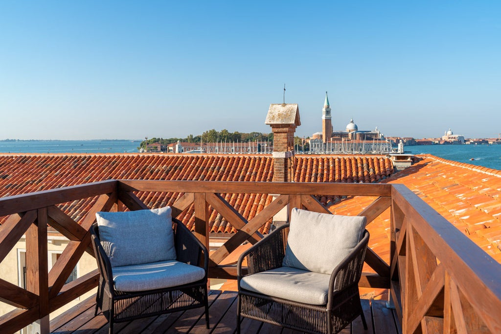 Elegant marble facade of Ca'Di Dio luxury hotel in Venice with ornate columns, arched windows, and warm evening lighting reflecting off water