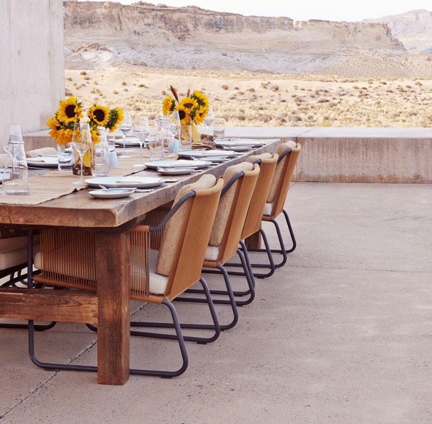 Minimalist desert luxury resort with angular concrete buildings seamlessly integrated into red rock canyons of Utah at golden hour