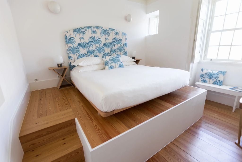 Bright, airy luxury hotel suite with rustic white walls, arched windows, freestanding bathtub and stunning ocean views of Lagos, Portugal