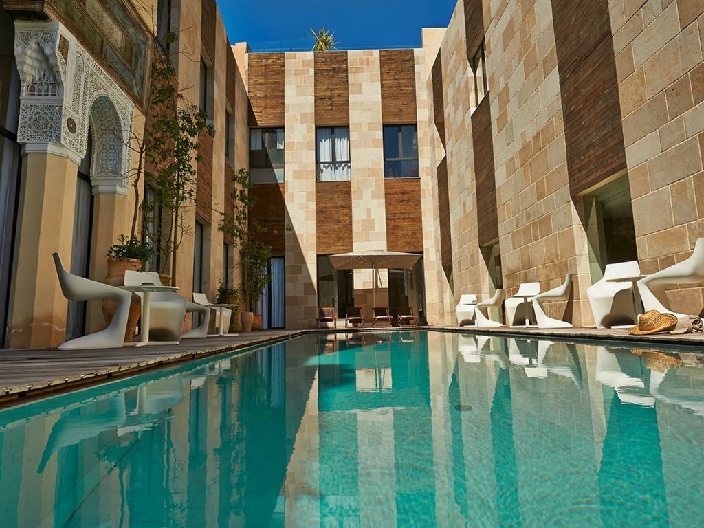 Elegant Moroccan-style deluxe superior room with intricate tile work, plush white bedding, and arched windows overlooking traditional architectural details