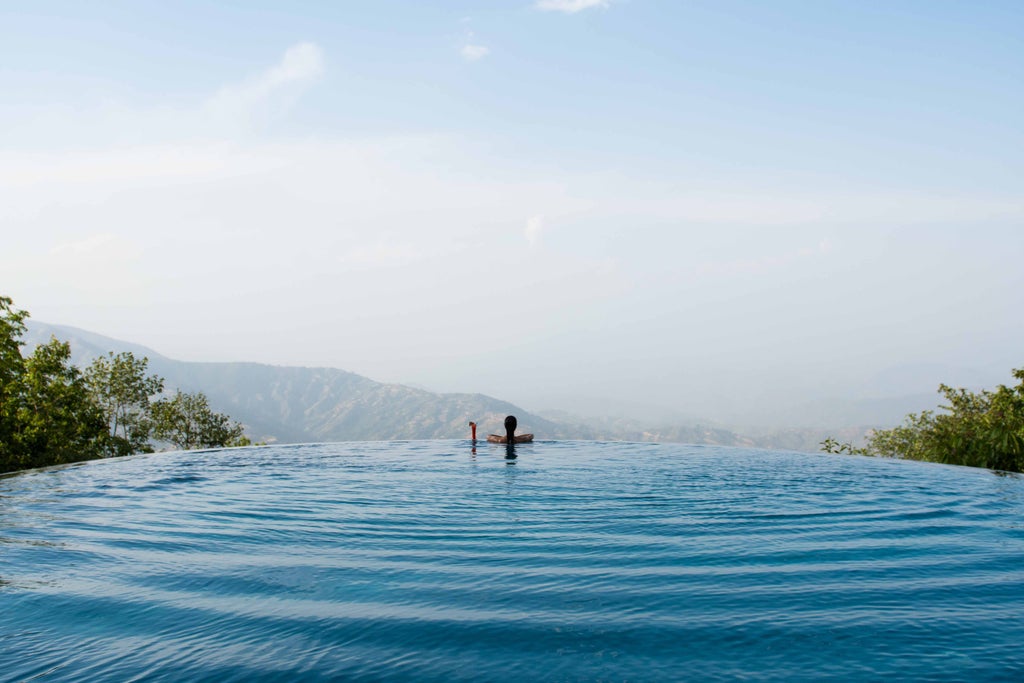 Luxury mountain resort with traditional Nepali architecture overlooking snow-capped Himalayas, featuring ornate wooden details and terraces