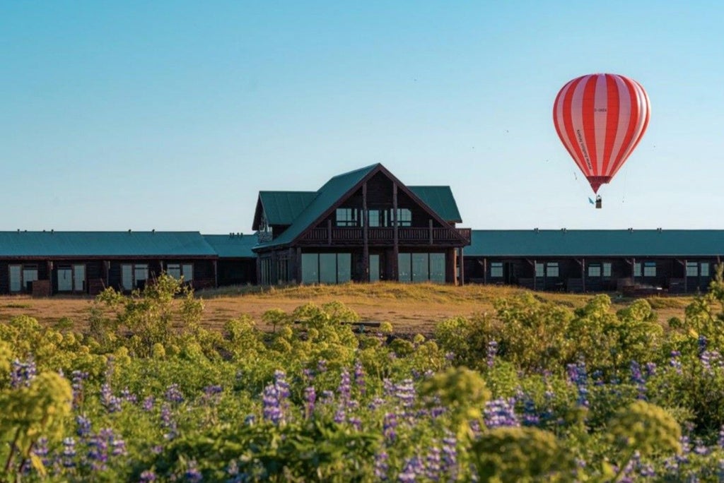 Luxurious rustic log hotel Hotel Rangá nestled in snowy Icelandic landscape at dusk, with warm glowing windows and mountain backdrop