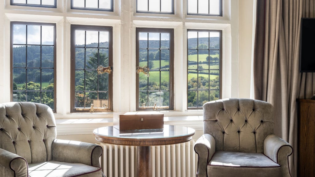 Elegant Valley Room at scenic Bovey Castle Hotel, featuring plush bedding, traditional decor, and expansive windows overlooking lush countryside landscape