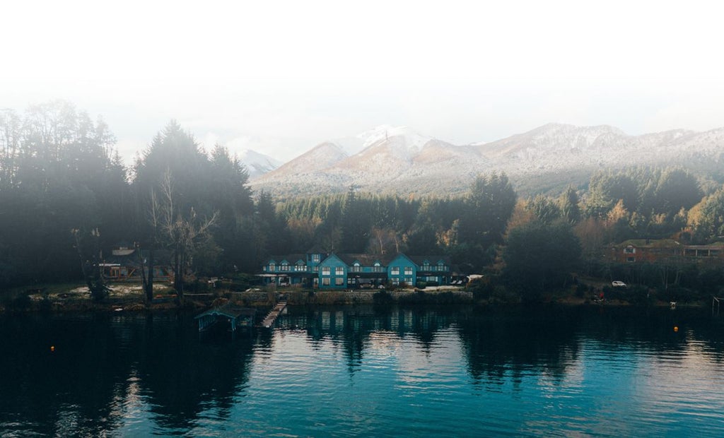 Luxurious lakeside hotel nestled in Patagonian landscape, with rustic wooden architecture, expansive lake views, and serene natural surroundings near Bariloche