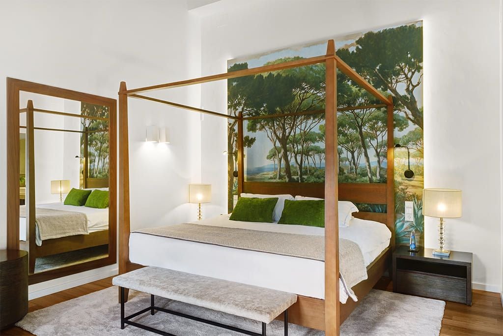 Elegant junior suite with modern Spanish design, white linens, wooden headboard, panoramic windows overlooking scenic Mediterranean landscape in Sóller, Mallorca