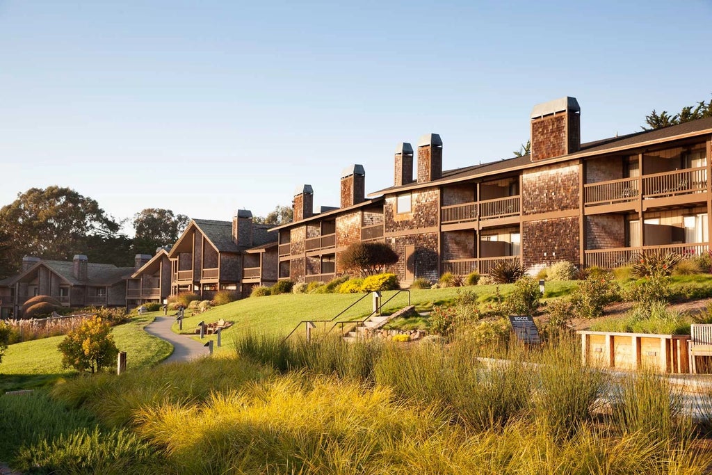 Rustic luxury lodge nestled on California coastline, featuring wooden architecture, panoramic ocean views, and natural pine forest surroundings at coastal retreat