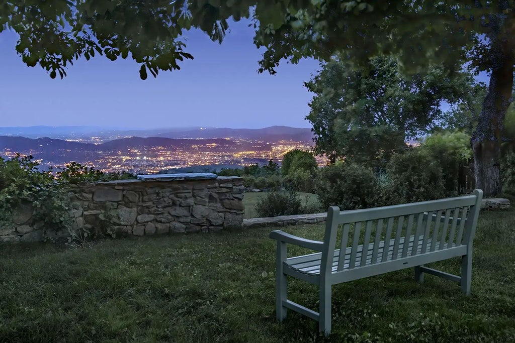 Luxurious Tuscan countryside hotel with rustic stone architecture, rolling green hills, and elegant cypress trees surrounding historic Italian villa