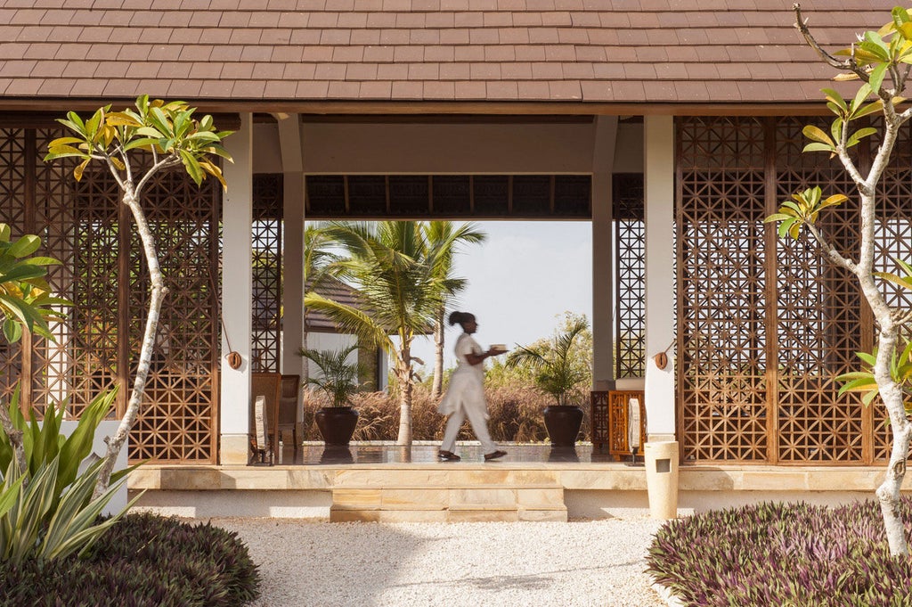 White-washed luxury villa with private pool overlooking turquoise ocean, surrounded by lush tropical gardens and palm trees at sunset