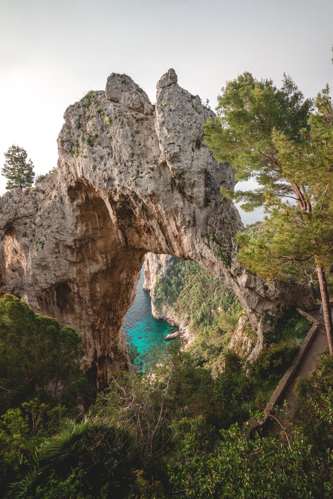 Luxurious coastal view of Capri, Italy, featuring rugged cliffs, turquoise Mediterranean waters, and elegant seaside villas nestled on hillsides