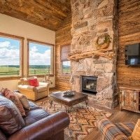 Rustic wooden lodge room with plush bedding, large windows overlooking scenic mountain landscape at scenset Mountain Ranch in western United States