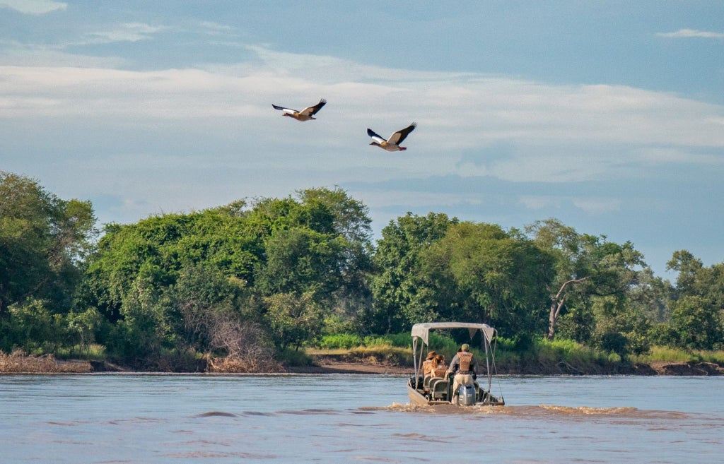 Luxurious safari tented camp nestled along the riverbank in South Luangwa National Park, with canvas tent and wooden deck overlooking lush wilderness