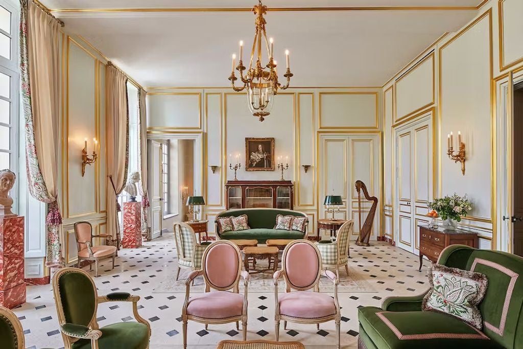 Opulent French château hotel with elegant stone facade, ornate windows, and manicured gardens overlooking Palace of Versailles grounds