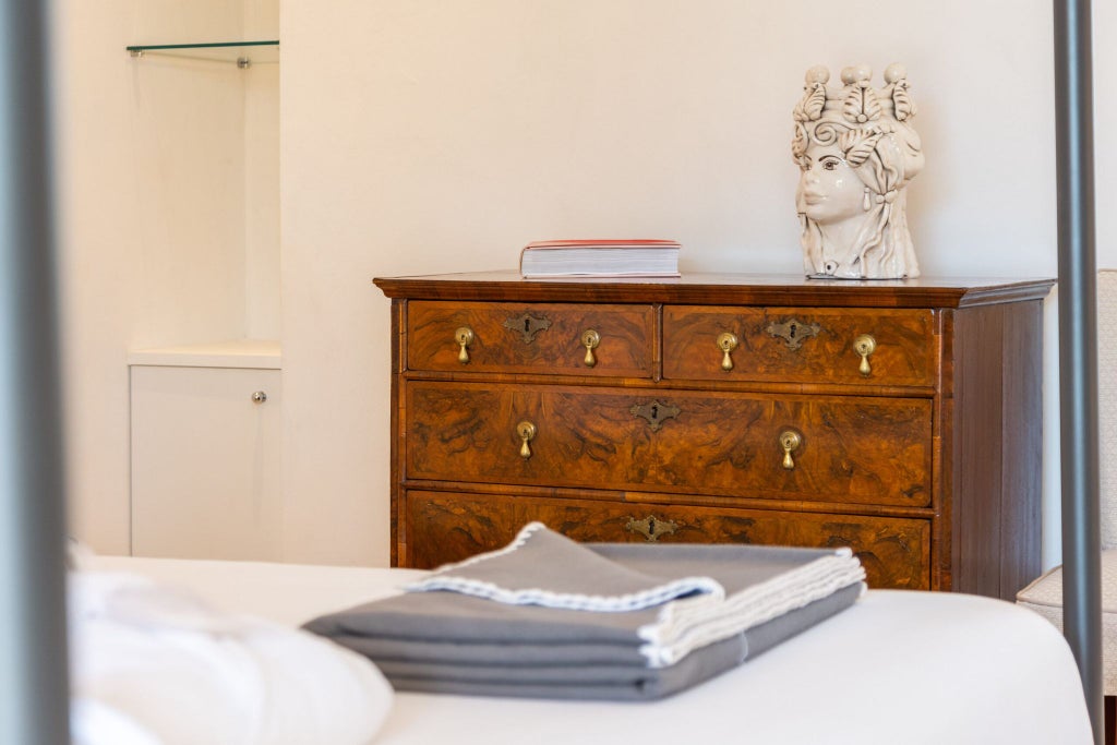 Elegant Sicilian hotel room with traditional white-draped four-poster bed, rustic stone walls, and soft natural lighting in Donna Coraly Resort, Syracuse