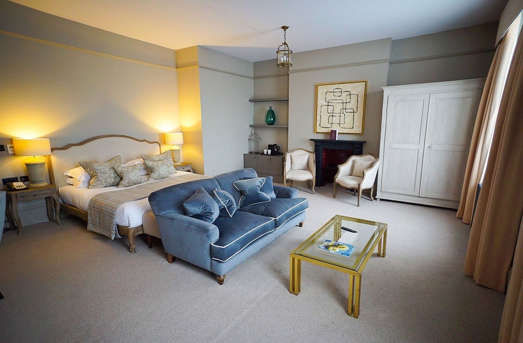 Luxurious hotel room with plush king-sized bed, rich wooden furnishings, soft neutral color palette, and elegant contemporary design at Kings Head Hotel, UK