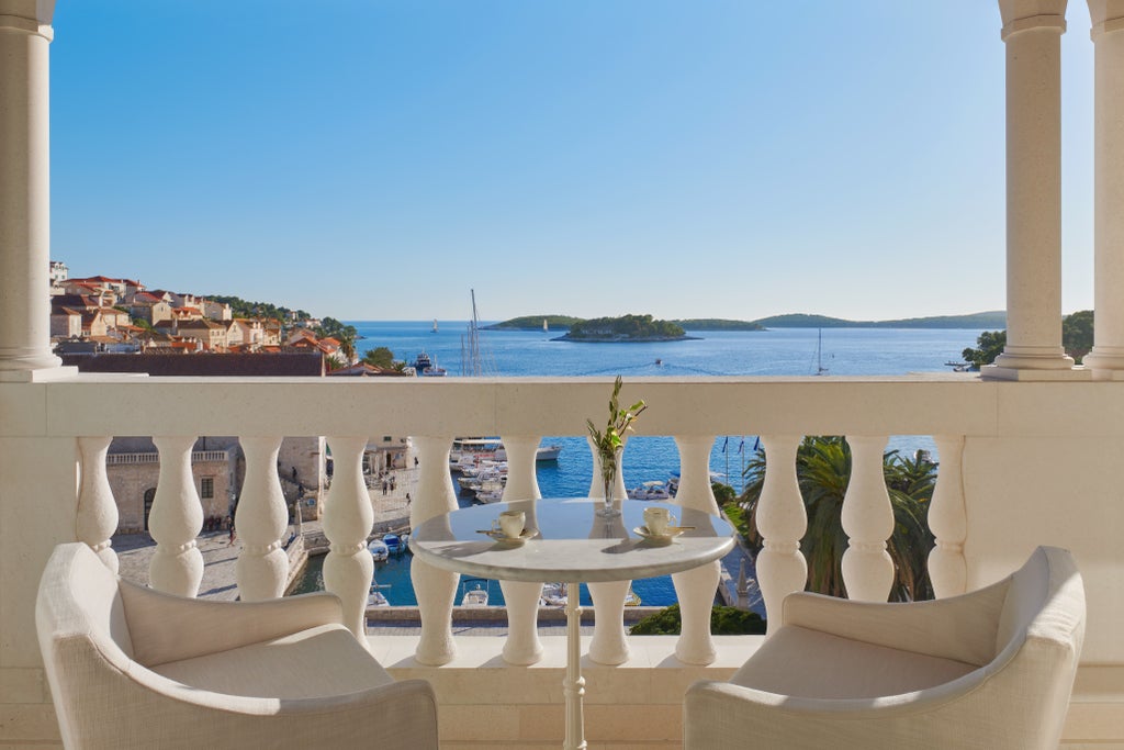 Elegant five-star Hotel Palace Elizabeth with ornate cream facade and wrought-iron balconies overlooking Hvar's main square at sunset